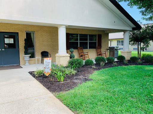 A welcoming porch with rocking chairs and beautifully landscaped greenery.