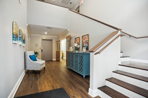 A beautifully designed foyer featuring a wooden staircase, blue storage cabinet, and cozy armchair.