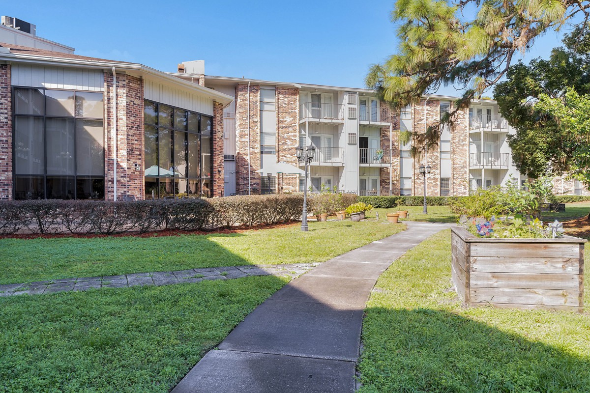 A residential apartment building with well-maintained gardens and a paved pathway.