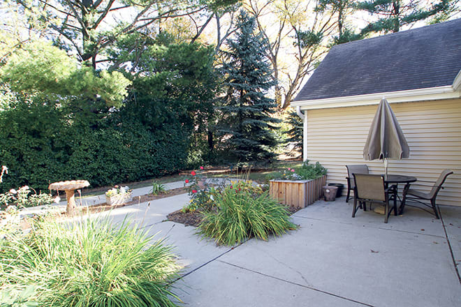 A serene backyard patio with outdoor furniture and lush greenery.