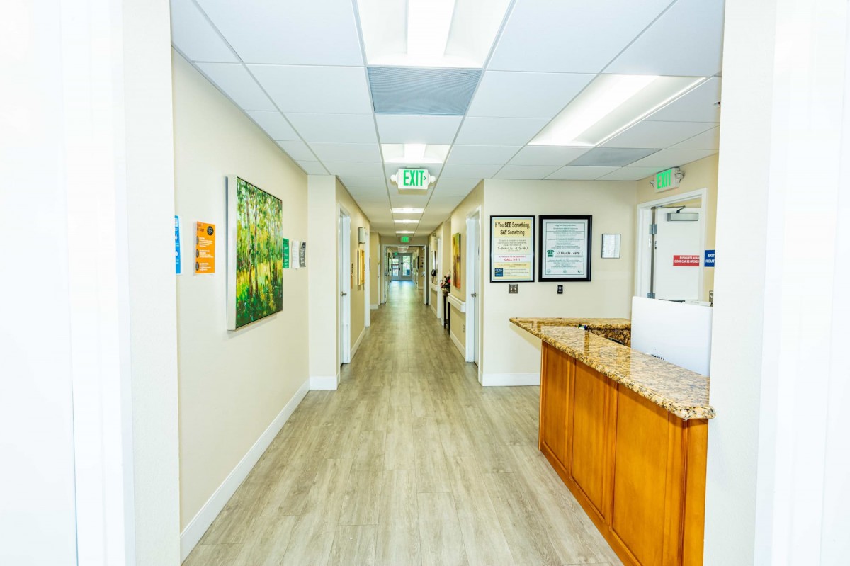 A brightly lit office hallway with a reception area and artwork on the walls.