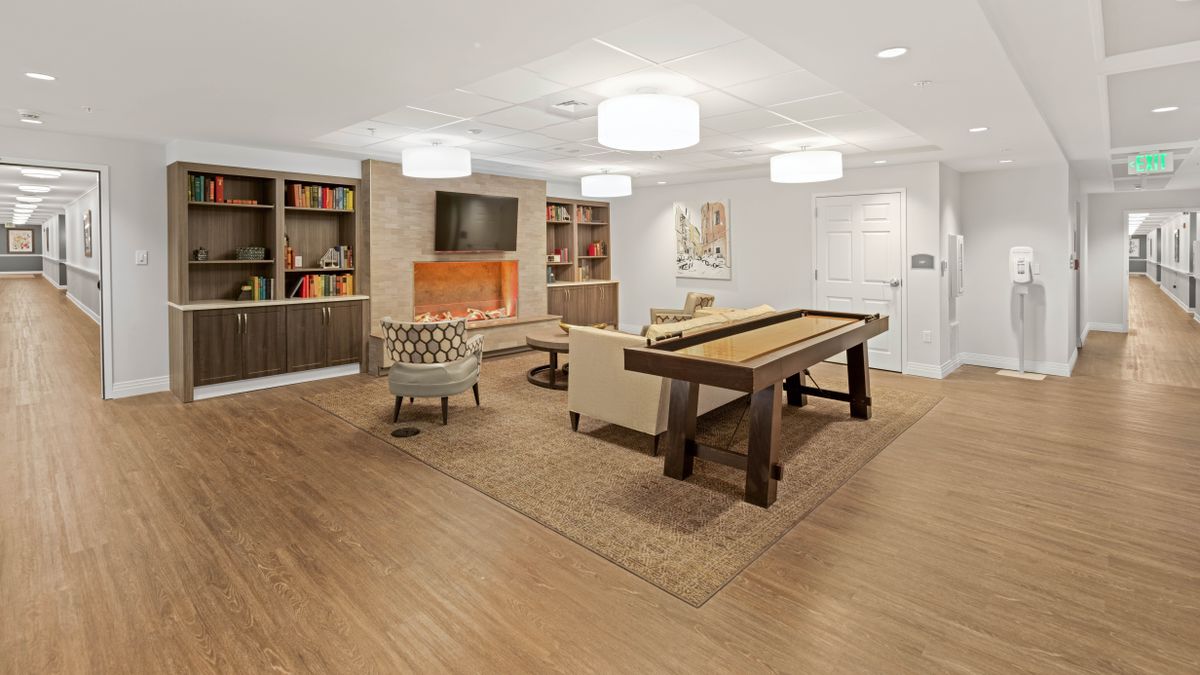 A modern living room with a shuffleboard table, cozy seating, and built-in bookshelves surrounding a fireplace.