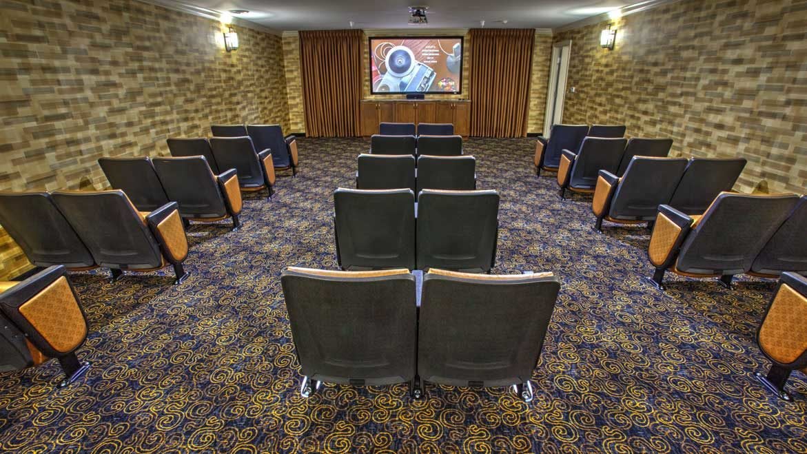 A small theater with arranged seating and a large screen at the front.