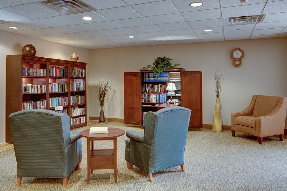 A cozy reading area with bookshelves, comfortable chairs, and a small table.