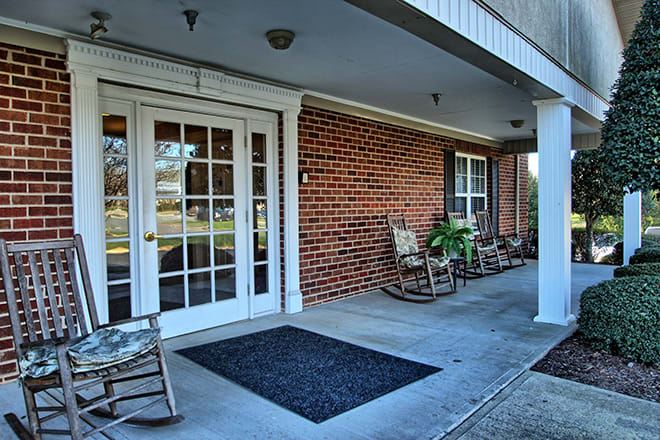 A welcoming porch featuring rocking chairs and a brick exterior.