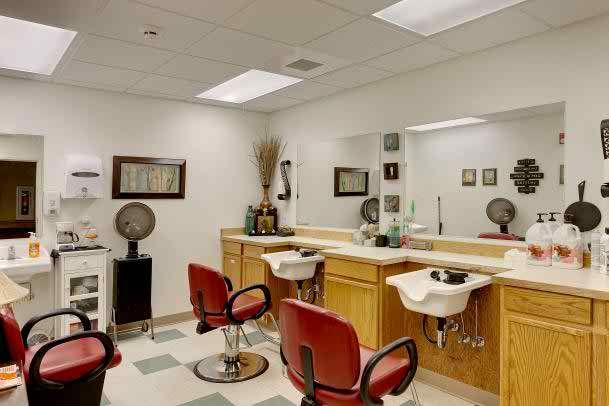 An empty hair salon with red chairs, mirrors, and hairstyling stations.