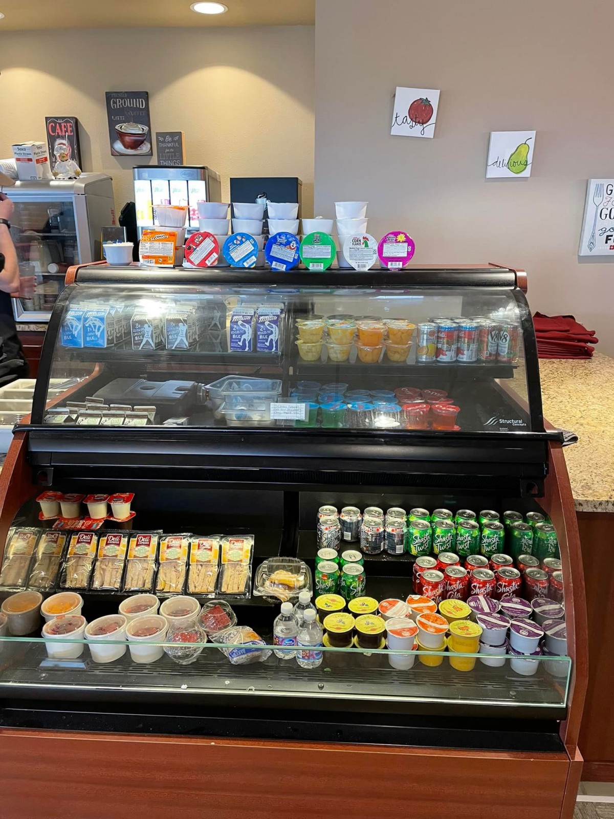 A refrigerated display case filled with assorted snacks and drinks in a cafe or store setting.