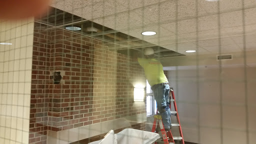 A worker performing ceiling maintenance while using a ladder.