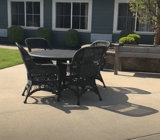 A sunny patio with wicker furniture set around a table.