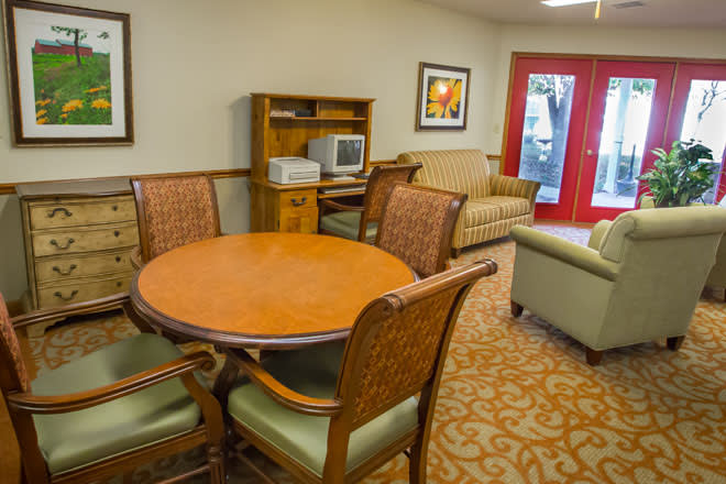 A cozy lounge area featuring a round table with chairs, couches, and a small shelf unit.
