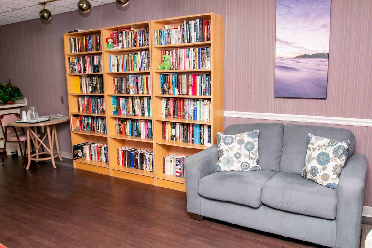 A cozy living room featuring a large bookshelf filled with books and a comfortable sofa.