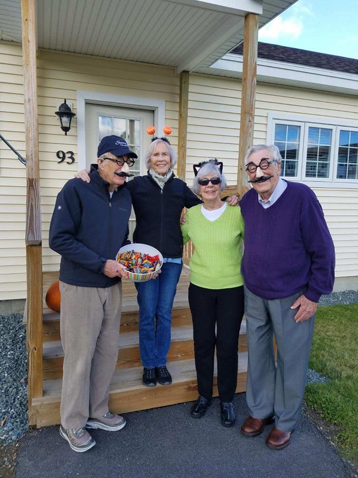 A group of four people in playful costumes standing outside a house.