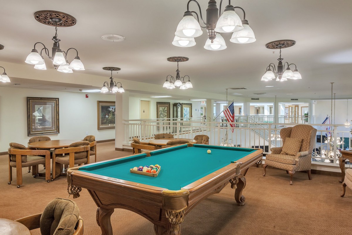 A well-lit game room featuring a classic pool table surrounded by comfortable seating.