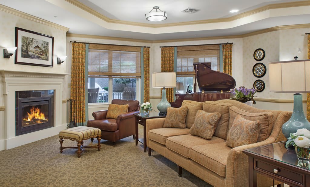 A cozy living room featuring a grand piano, comfortable seating, and warm decor.
