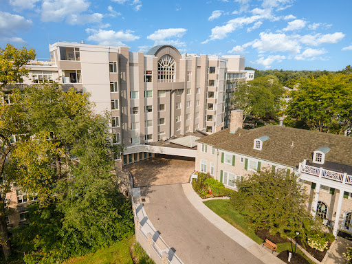 A modern residential building surrounded by lush greenery and a clear blue sky.
