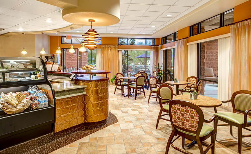 A cozy cafe interior featuring tables and chairs with warm lighting.