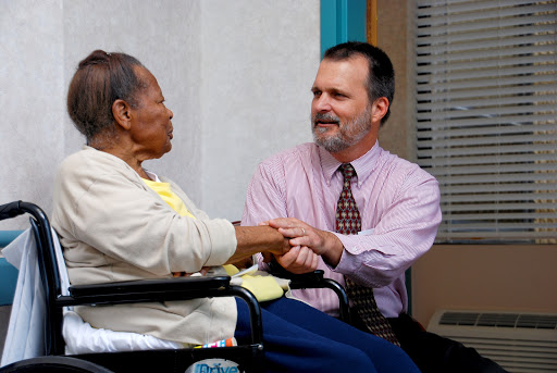 A caregiver engages in a warm conversation with an elderly woman in a wheelchair, showcasing compassion and connection.