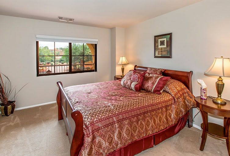A cozy bedroom with a large bed, decorative pillows, and a window view.