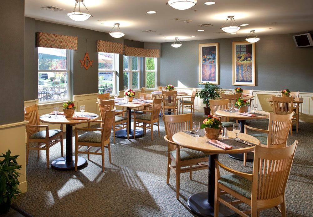 A cozy restaurant interior with wooden tables and chairs, decorated with plants and art on the walls.