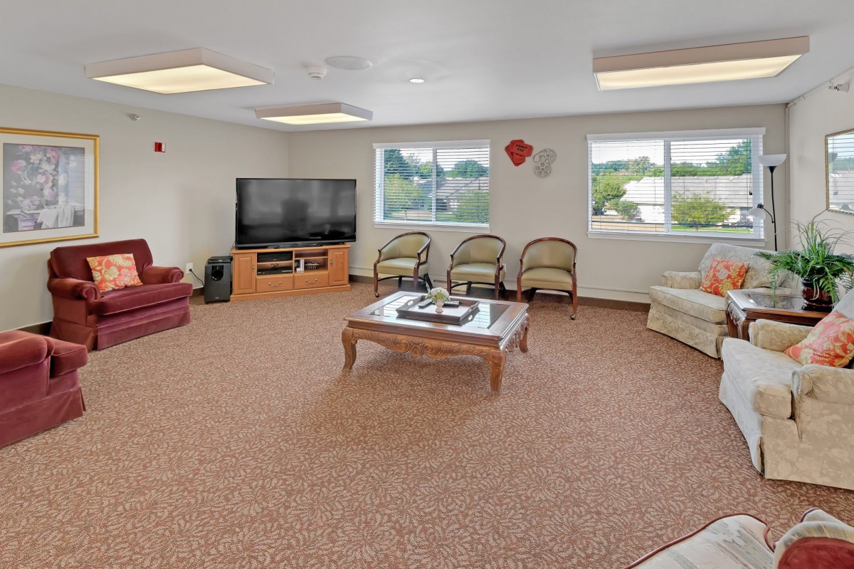 A spacious living room with a large television, comfortable seating, and ample natural light.