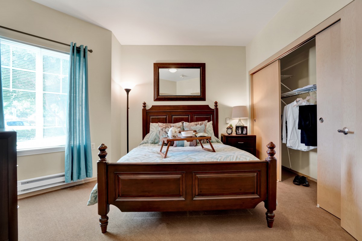 A well-decorated bedroom with a wooden bed, mirror, and closet.