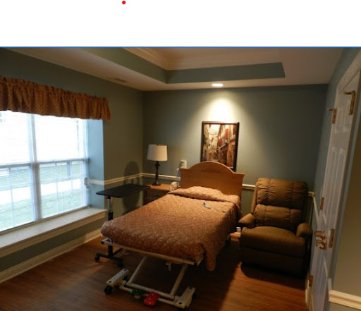 A comfortable hospital room featuring a patient bed, recliner chair, and a view outside.