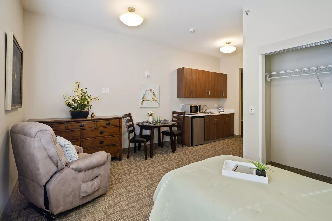 A cozy studio apartment featuring a living area with a sofa, a small dining table, and a kitchenette.