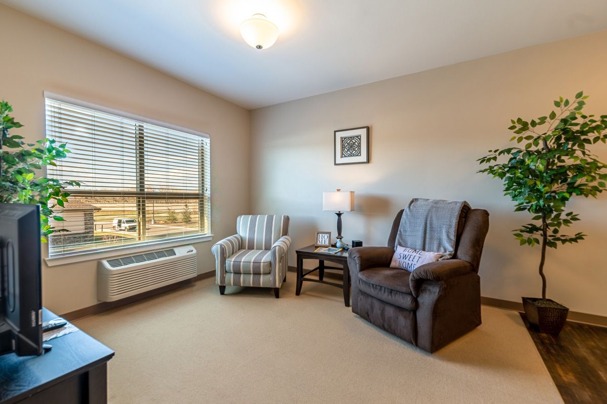 A cozy living room with two armchairs and a large window allowing natural light to fill the space.