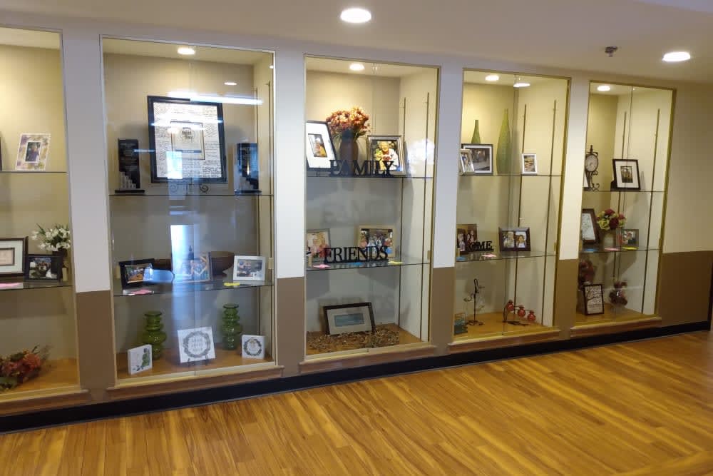 A glass display case showcasing various trophies, awards, and memorabilia on a wooden floor.