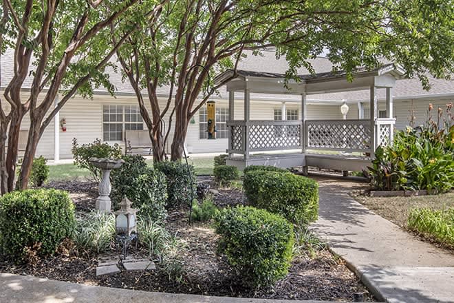 A peaceful garden setting with a gazebo and manicured shrubs.