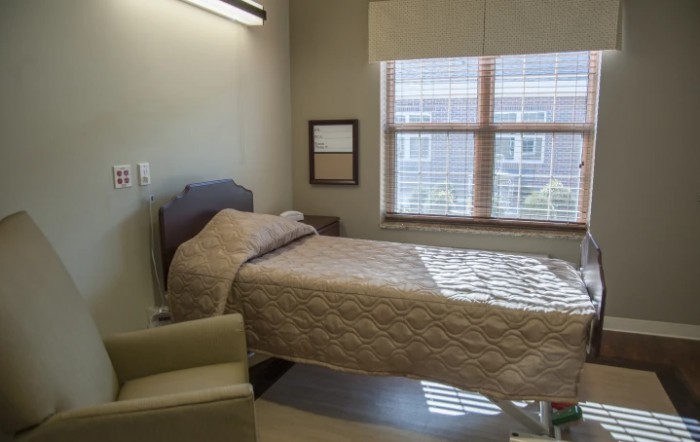 A hospital room with a single bed and large window.