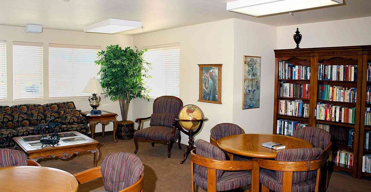 A cozy office interior with a meeting area, featuring round tables, chairs, a globe, and artwork on the walls.