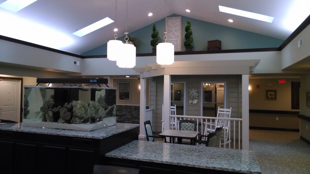 A modern interior featuring a spacious open kitchen and living area with stylish lighting and an aquarium.