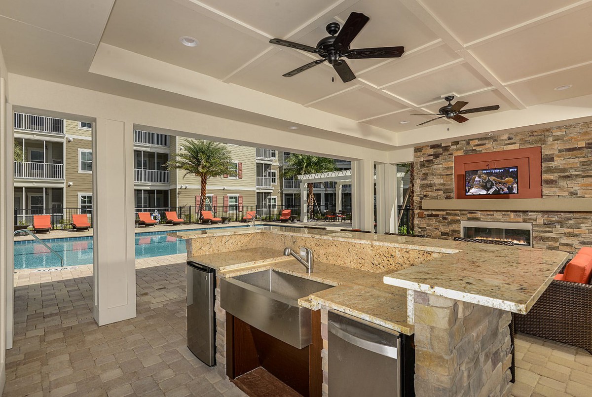 A luxurious outdoor kitchen and entertainment area next to a pool.