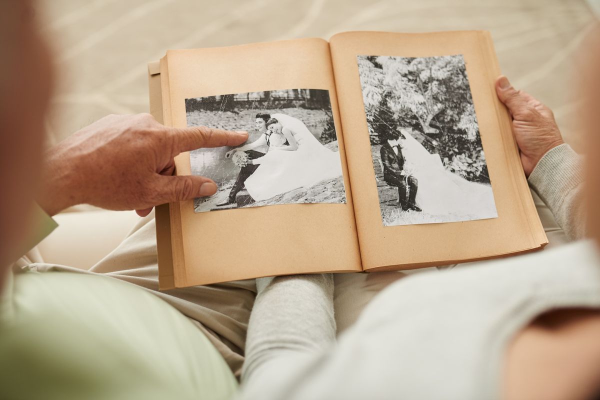 A person flips through a vintage photo album filled with wedding memories.