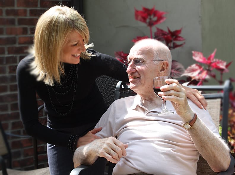 A caregiver shares a moment of joy with an elderly man outdoors.