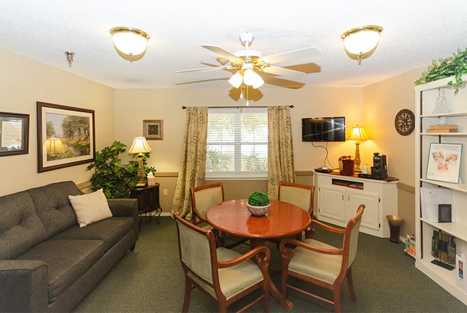 Cozy living room with a round table, chairs, sofa, and a wall-mounted television.