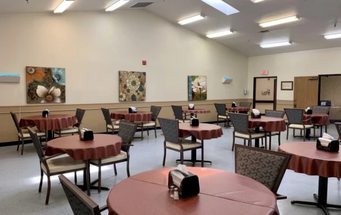 A cozy dining room with neatly arranged tables and chairs, adorned with decorative wall art.