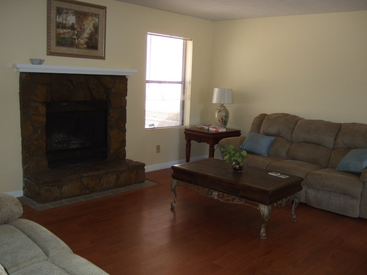 A cozy living room with a fireplace, sofa, and wooden coffee table.