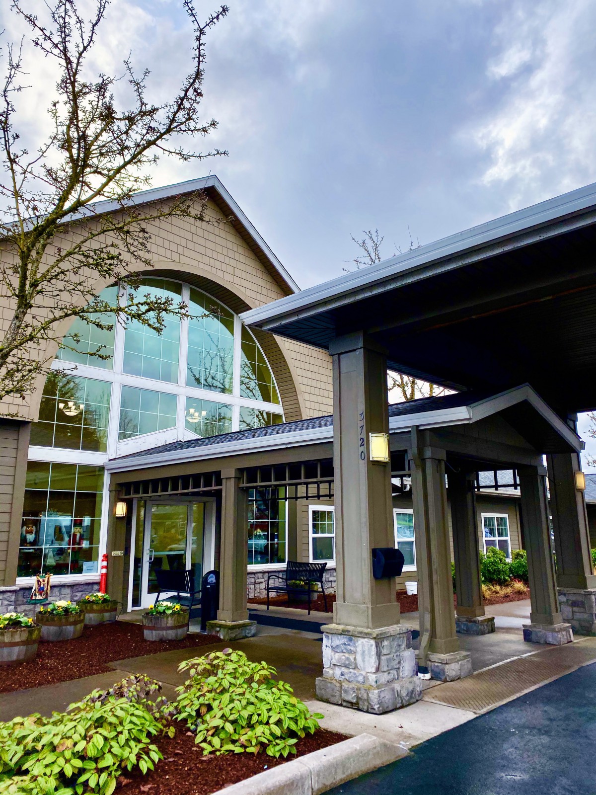 A modern building entrance with large glass windows and a covered entryway.