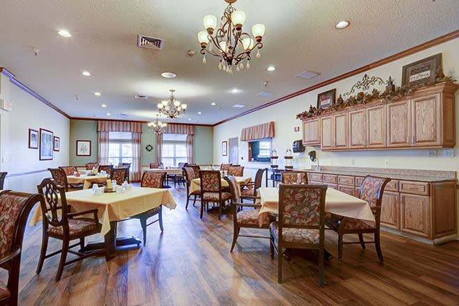 A cozy dining area with chandeliers, wooden flooring, and elegantly decorated tables and chairs.