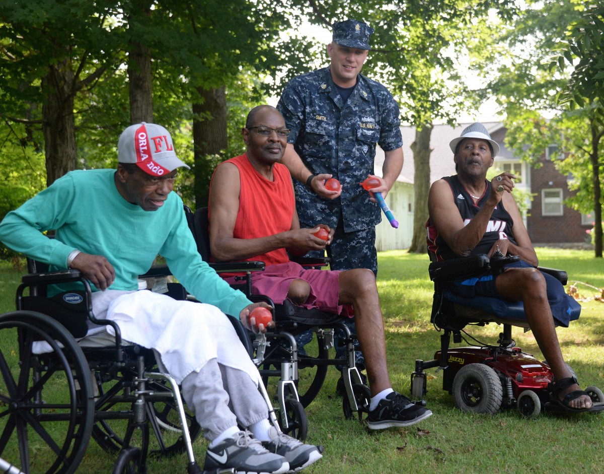 A group of people, including a person in military uniform, enjoying time together outdoors in wheelchairs.