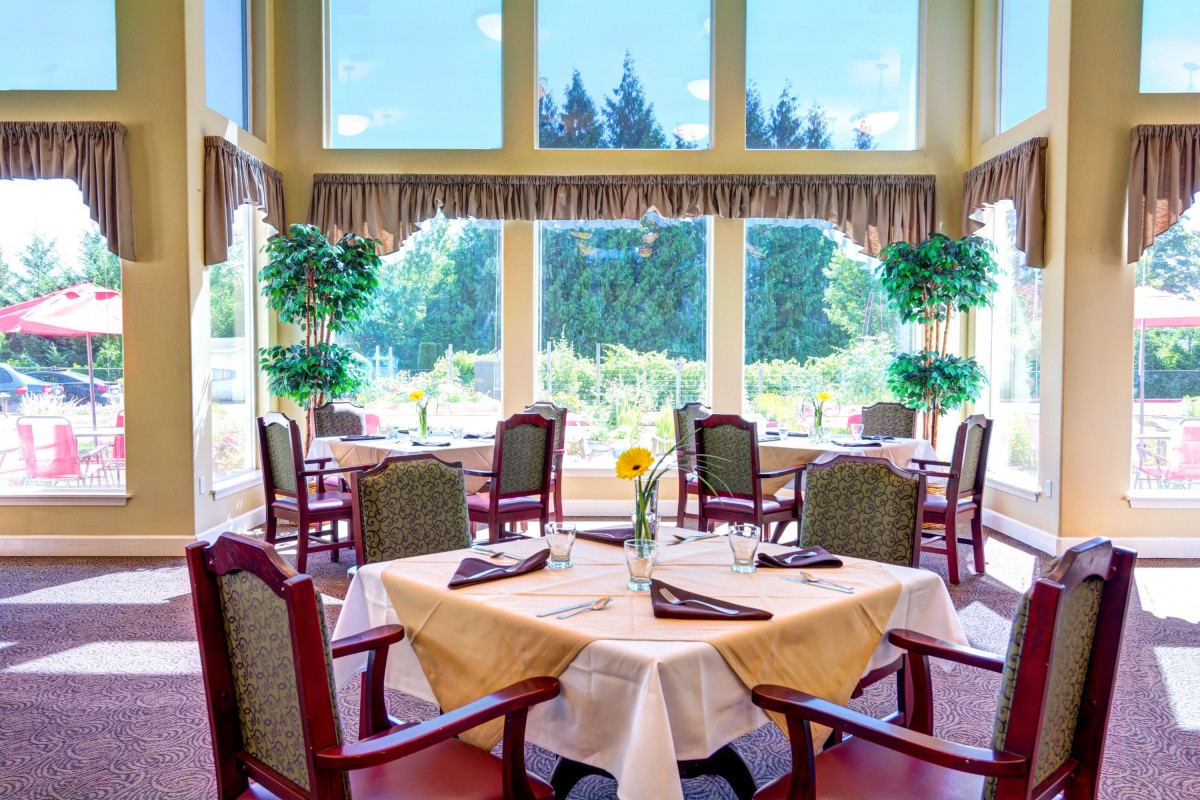 A bright and inviting restaurant dining area with well-arranged tables and large windows.