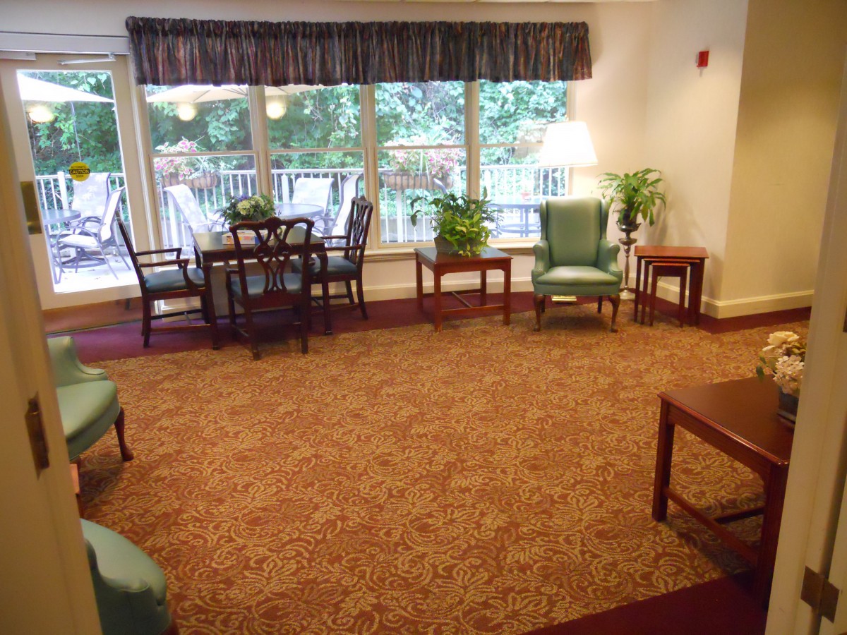 A cozy living room with ample seating, large windows, plants, and a dining table.