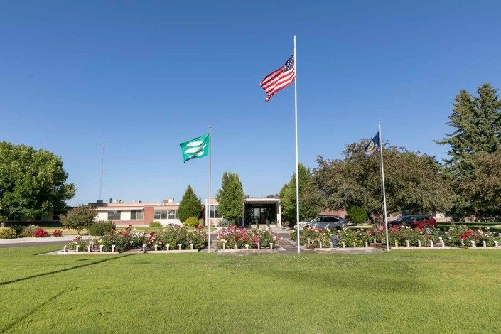 A building with flags flying in front on a sunny day.