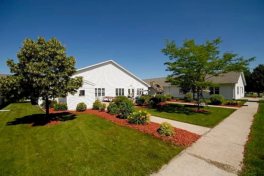 A picturesque suburban house with a well-maintained lawn and garden under a clear blue sky.