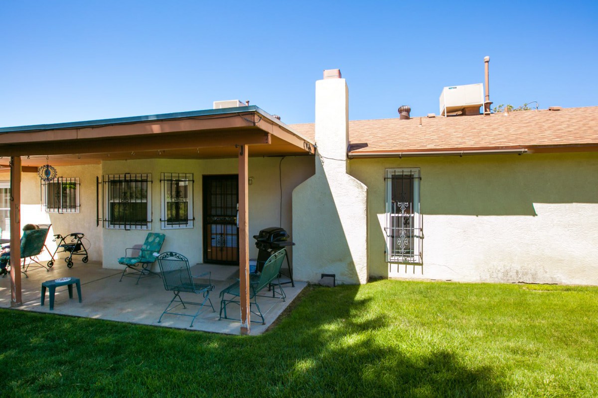 A cozy backyard with a patio featuring outdoor furniture and a well-maintained lawn on a sunny day.