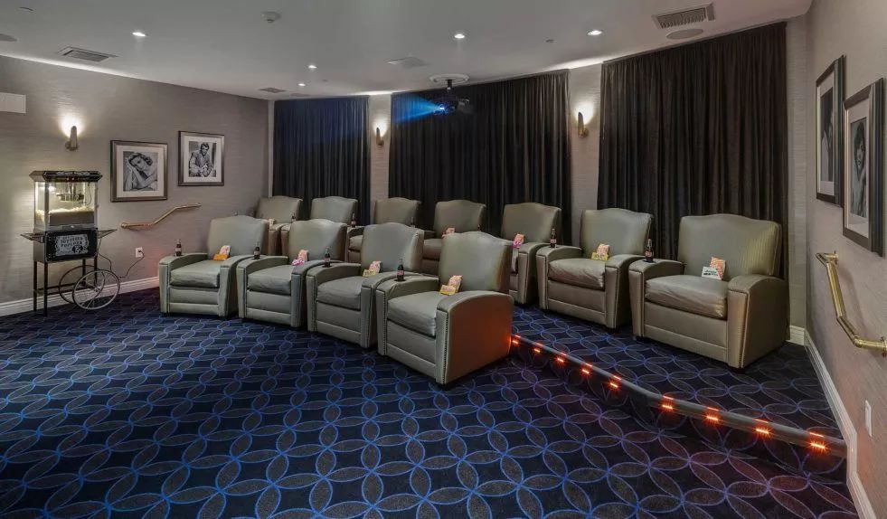 A cozy home theater room with rows of plush recliners and a large projection screen.