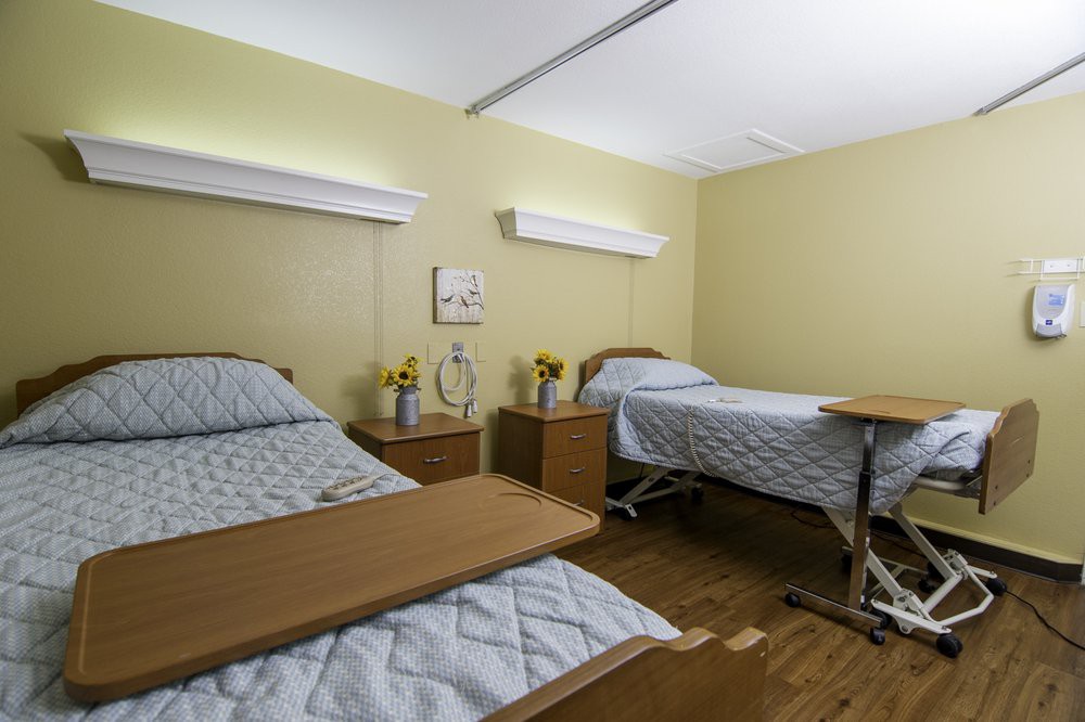 A clean hospital room with two beds and nightstands.