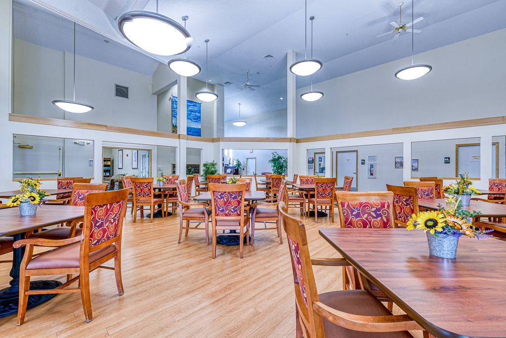 A spacious dining hall with wooden tables and chairs, illuminated by decorative lighting fixtures.